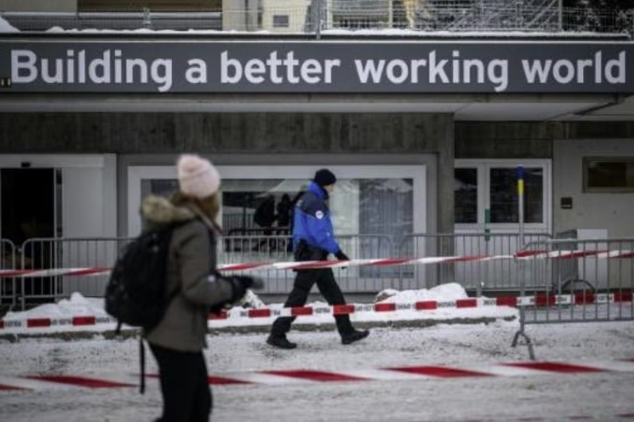 Un policía pasa frente a un cartel con la frase "Construyendo un mejor mundo del trabajo" el 16 de enero de 2023 en la localidad suiza de Davos