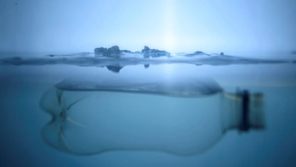 Una botella de plástico flota debajo de una capa de hielo