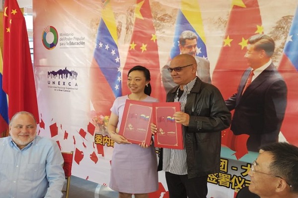 La presidenta de la Corporación Asia Gourmet Market, Michelle Zhang y el rector de la UNEXCA, Rubén Reinoso, muestran el acuerdo firmado.