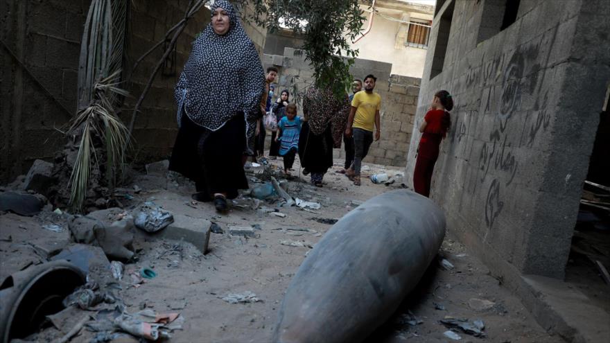 Los palestinos observan una bomba sin explotar lanzada por un avión de combate israelí F-16 en el barrio Rimal de la ciudad de Gaza
