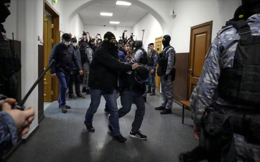 Un sospechoso de participar en el mortal ataque a un centro de conciertos en Moscú es escoltado por agentes de policía en el tribunal de Basmanny, en Moscú.